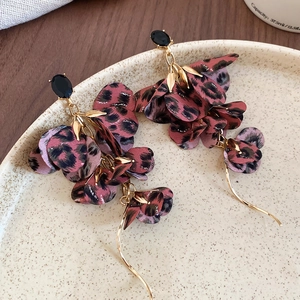 Detail of leopard print fabric flower earrings with long gold tassels on ceramic tray