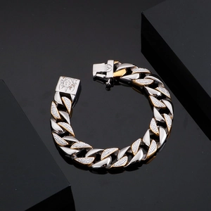 Macro view of two-tone iced out Cuban link bracelet with sun head engraving on clasp