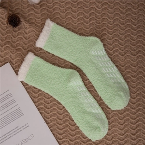 Detail of mint green fuzzy slipper socks with white faux fur cuffs and non-slip grippers