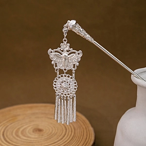 Silver butterfly hair stick with turquoise flower patterns and long tassels in a ceramic vase