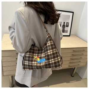 Close-up of brown checkered tote bag with cartoon dog embroidery and shoulder strap