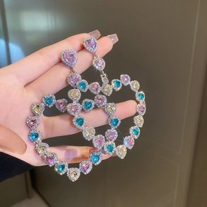 Détails macro de boucles d'oreilles cœur de luxe avec strass colorés brillants