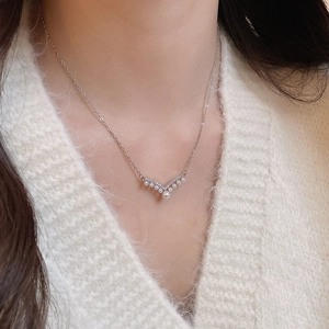 Close-up of elegant V-shaped necklace with pearls and zircons on a knit sweater