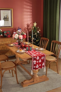 Detail of red Christmas table runner with white snowflake patterns and tassel accents