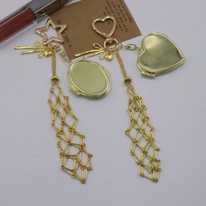 Detail of gold metal mesh pendant with star and heart carabiner for bags and lipstick