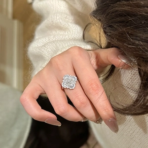 Close-up of a silver four-leaf clover ring featuring sparkling zircon stones on a hand