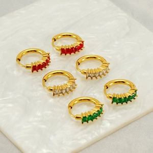 Gros plan de boucles d'oreilles créoles dorées avec zircons rectangulaires rouges et verts