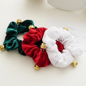 Detail of velvet Christmas scrunchies in red green and white with gold bells