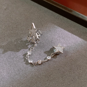 Detail of silver star magnetic ear clip with zircon chain link on textured stone