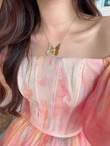 Macro shot of gold butterfly pendant necklace with hammered texture on a female neck