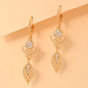 Macro shot of gold-plated drop earrings featuring zircon-studded butterfly and leaf charms