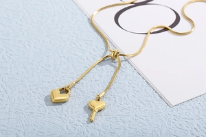 Makro-Detail einer goldenen Schlangenkette mit Herzschloss und Schlüsselanhänger