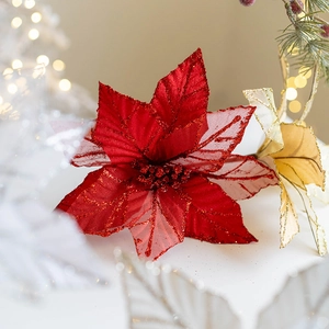 Red velvet mesh Christmas flower with gold leaves and glitter on festive bokeh background