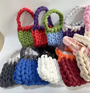 Detailed view of assorted colorful chunky knit bags featuring braided handles and yarn textures
