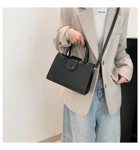 Detail of elegant black square handbag with crocodile texture and gunmetal hardware buckle