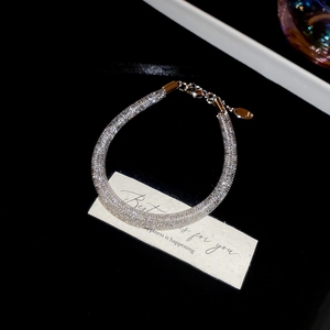 Detailed view of silver mesh tube bracelet with sparkling crystals on black background