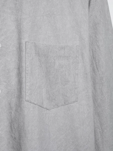 Detail of grey shirt showing fabric texture and pocket stitching with a minimalist feel