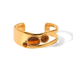 Detail of gold open bangle with wavy lines and three brown tiger eye gemstones