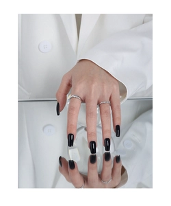 Close-up of minimalist silver rings with micro-inlaid zircons on model with black nails
