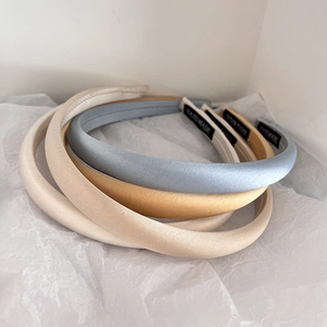 Detail of four handmade satin headbands in beige and light blue on white background