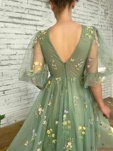 Close-up of green tulle evening dress back with floral embroidery and V-neck design