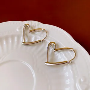 Boucles d'oreilles cœur argentées ajourées présentées sur un plateau en céramique