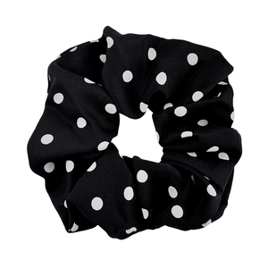 Elastic black and white polka dot fabric scrunchie for ponytails shown on white background