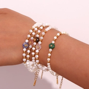 Detail of 5-piece beaded bracelet set with white pearls and colorful charms on wrist