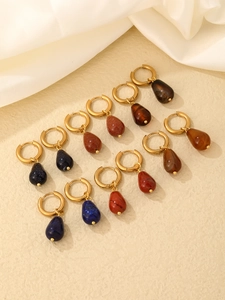 Flat lay of colorful teardrop stone earrings with gold hoops on beige texture