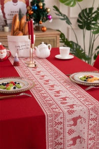 Detailed close-up of red Christmas table runner with knitted reindeer and tree patterns