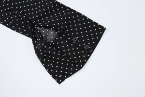 Dettaglio macro di maniche in chiffon a pois neri con bottoni decorativi fini