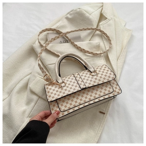 Detail of cream crossbody bag with brown geometric dots on a beige blazer background