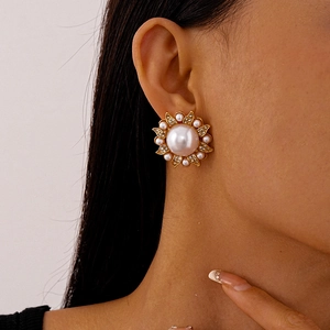 Close-up of vintage flower earrings with central white pearl and sparkling rhinestones