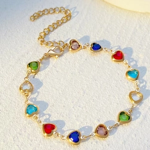 Colorful heart-shaped crystal bracelet with gold chain under natural warm sunlight