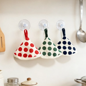 Three colorful polka dot heat resistant pot lid handle covers hanging in a kitchen