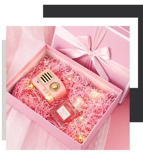 Close-up of pink gift box with vintage mini speaker, shredded paper, and LED fairy lights