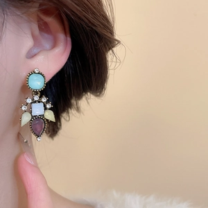 Macro detail of retro vintage drop earrings with colorful zircon gemstones on model