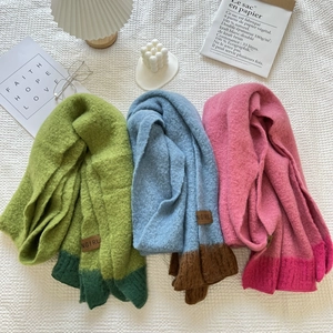 Close-up of soft cashmere-feel knitted scarves in color-block designs with logo labels