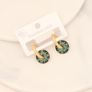 Detail of stainless steel earrings with gold plating and green sunburst enamel charm