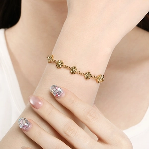 Dettaglio ravvicinato del bracciale dorato a maglie di girasole indossato al polso