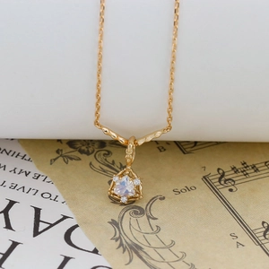 Dettaglio della collana dorata con pendente triangolare in pietra di luna e diamanti
