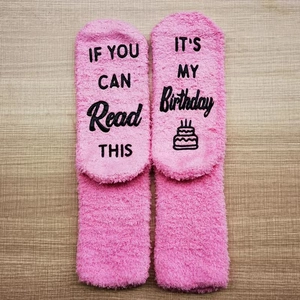 Pink coral fleece birthday socks with funny text on wooden background