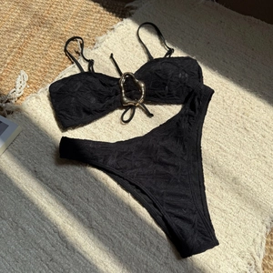 Detail of black textured bikini fabric with golden metal ring and ribbed finish