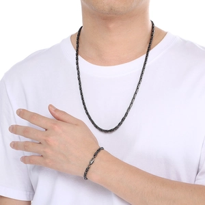 Gros plan d'un ensemble collier et bracelet pour homme en acier titane noir forme en U