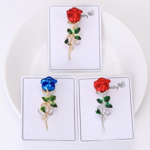 Three elegant rose brooches in red and blue colors displayed on white cards in a plate