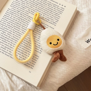 Close-up of cute plush fried egg keychain with smiley face on a vintage book