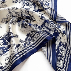 Detailed view of silk scarf with blue tree patterns and smooth glossy fabric texture
