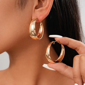 Close-up of elegant gold hoop earrings worn by a model showcasing polished metallic finish
