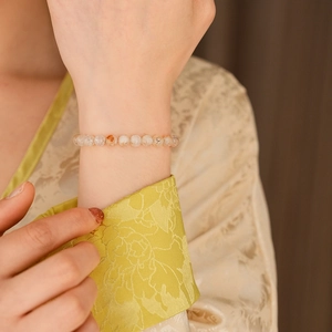 Détail d'un bracelet en perles de pierres précieuses porté avec cristaux ambrés chauds