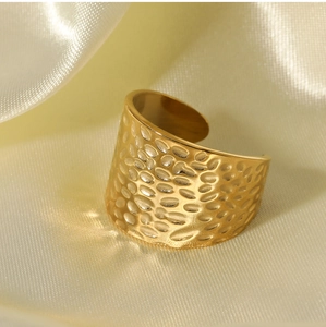 Macro detail of golden hammered texture and wide open adjustable band on stainless steel ring